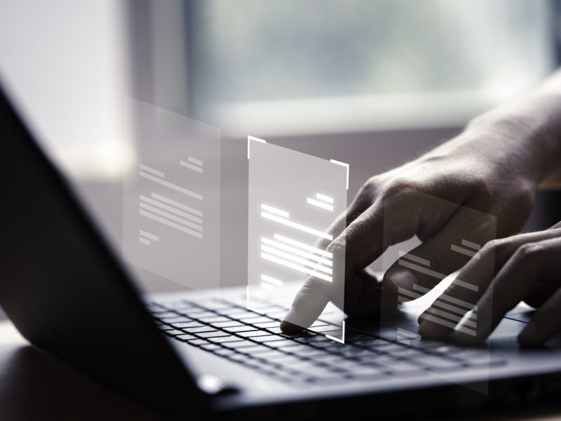 Hand using laptop computer with virtual screen and document for online approve paperless quality assurance and ERP management concept.